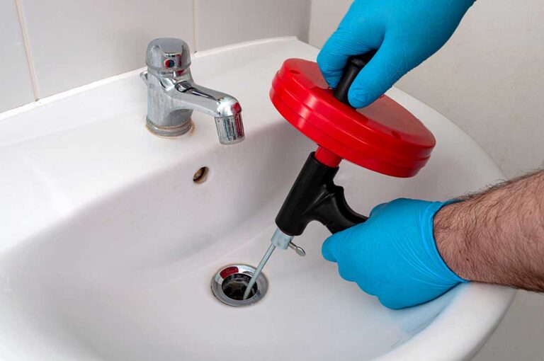A person installing an under-sink water filter with basic plumbing tools in a home kitchen.