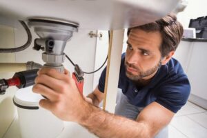 A homeowner examining standing water in a basement laundry area near a floor drain.