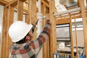 A homeowner inspecting water-damaged drywall near a baseboard with visible discoloration and warping.