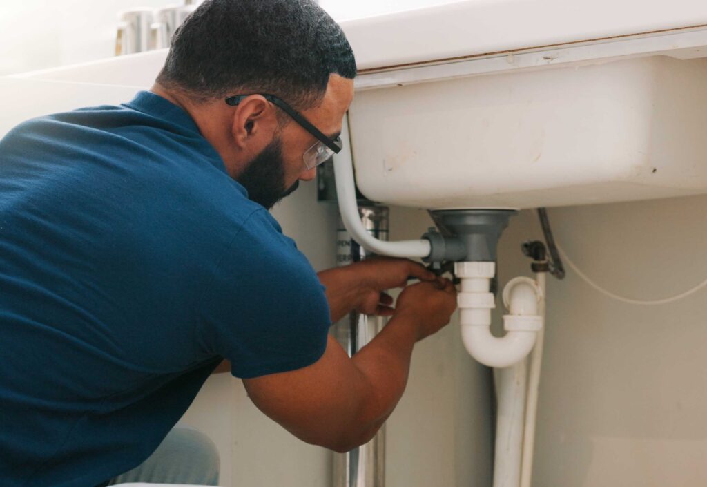 A homeowner checking a water heater tank in a residential utility room.