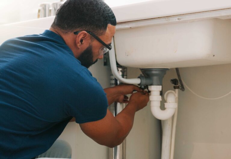 A homeowner checking a water heater tank in a residential utility room.