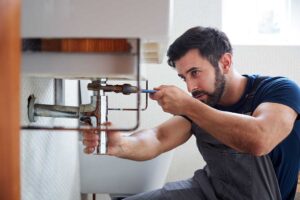 Person wearing gloves scrubbing a rubber splash guard from a kitchen sink garbage disposal.